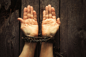 tied hands with rope of old woman on wooden background
