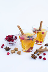 Hot tea with lemon, cinnamon, cranberry and anise in the glass cups on the white background. Close-up. Winter drink.