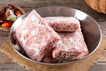 Frozen ground meat, minced pork in a metal bowl. Ground chicken inclusive backs, necks, liver and heart. Frozen food. Concept for raw food diet for cats, dogs and pets.
