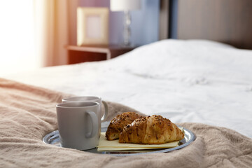 Guest welcome, two cups and croisants on the plate on bed in bedroom