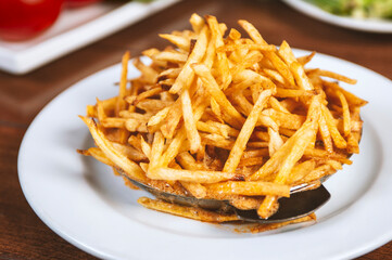 Fried French fries in metal bowl.Unhealthy junk food prepared in deep fryer oven for dinner in American restaurant.