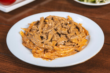 Beef Stroganoff with french fries in white plate.