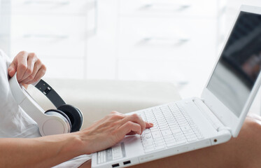 Woman sitting on sofa typing on laptop with headphones,dating