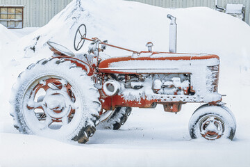 An old antique tractor covered in snow. - 471541540
