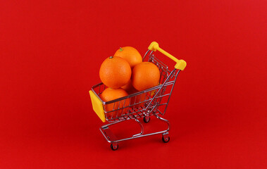 Tangerines in a shopping cart on a red background