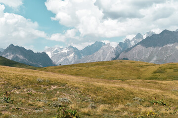 Summer mountain landscape near Mestia, Svaneti region, Georgia, Asia. Snowcapped mountains in the background. Blue sky with clouds above. Georgian travel destination