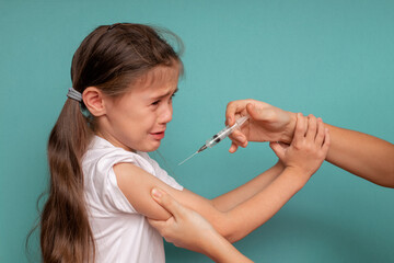 A little girl cries not wanting to be vaccinated against coronavirus, refusing vaccination against...