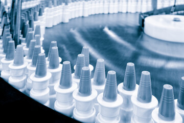 Close-up Many white plastic spray bottles for packaging liquid medicines or cosmetics in a row on a conveyor belt in a pharmaceutical manufacturing factory