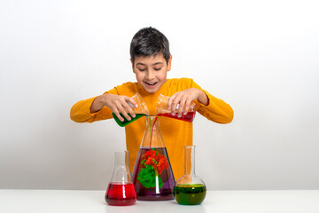 A schoolboy conducts experiments with a multi-colored liquid in flasks.