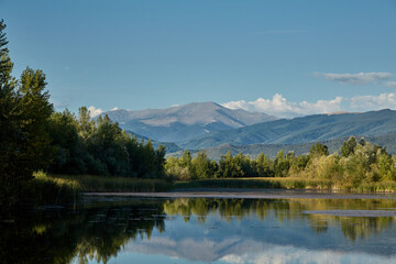 Fototapeta na wymiar Mount Parang is reflected in the water of a lake near Bumbesti-Jiu, Romania.