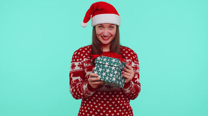 Lovely smiling teen girl 20s in red Christmas Santa deer sweater getting present gift box, expressing amazement extreme happiness isolated on blue background. Happy New Year celebration merry holidays