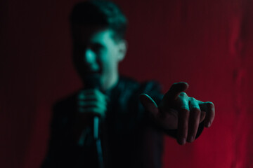 Close up portrait Rock band vocalist singing to microphone in lights on red background