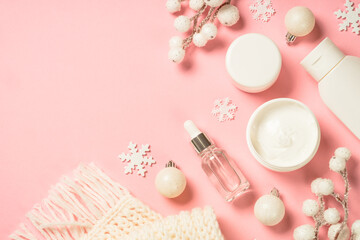 Fototapeta na wymiar Winter cosmetic, skincare product. Cream, serum, tonic with winter decorations. Top view on pink background with copy space.