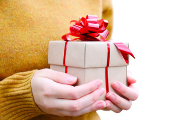 A gift in the hands of a girl. To give gifts. Congratulations. Celebrating Christmas, New Year. A greeting card. A gift box made of craft paper with a red bow.