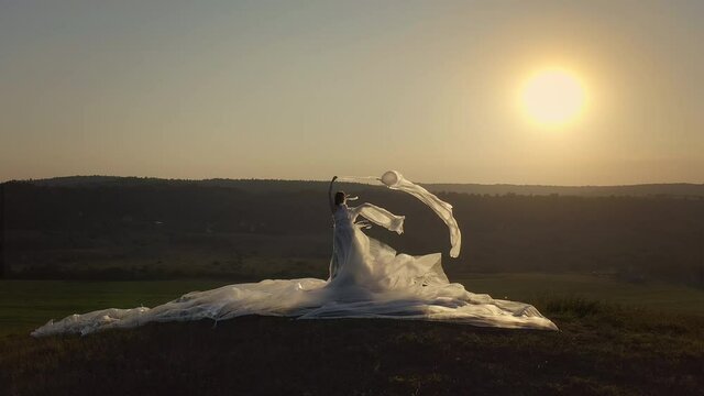 Beautiful Young Girl In Polyethylene Dress. Wind Blows Long Dress. Environmental Protection Concept. Girl Like Earth Is Wrapped In Polyethylene. Sunset.