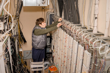 Fototapeta na wymiar The technician is laying communication lines by conducting internet telephony. servicing the Automatic Telephone Station in the server room.