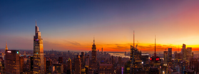 Panoramic view of Manhattan at sunset.  Among the buildings seen are the Empire State Building, the One World Trade Center and the new One Vanderbilt building.  