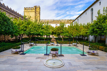 Patio with fountains and orange trees next to the wall of the Alcazar of Cordoba in Spain.