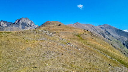 A panoramic view on the green hills and sharp ridges of the mountain peaks of the Chaukhi massif in the Greater Caucasus Mountain Range in Georgia, Kazbegi Region. Wanderlust. Clear Sky. Hike