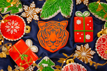 Banner for Christmas and New Year gingerbread tiger symbol Chinese zodiac calendar 2022 and gingerbread cookies snowflakes, Christmas trees, garlands on blue silk fabric background