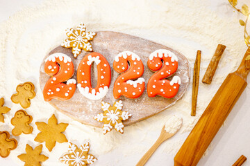 Banner for Christmas and New Year gingerbread cookies numbers 2022, snowflakes on a wooden cutting board sprinkled with flour next to a rolling pin and cinnamon sticks