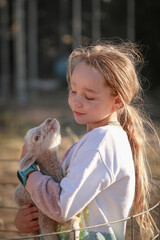 Farm girl holding newborn baby lamb