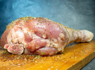 Turkey drumsticks in spices lie on a kitchen cutting board.  Turkey leg. Juicy meat is waiting to...