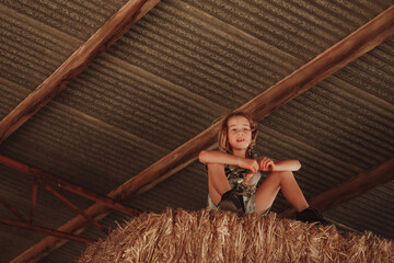 Young farm boy playing on hay stack on country property