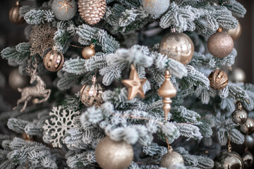 Close-up of a festively decorated outdoor Christmas tree with balls on a blurred sparkling fairy background. Defocused garland lights, bokeh effect.