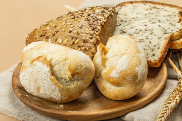 Freshly baked bread with wheat ears, buns, and toasts. Assorted bakery on light beige background