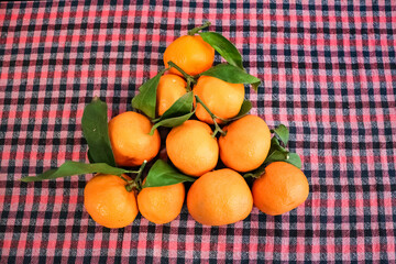 Appetizing orange tangerines (mandarins) with leaves on a textile tablecloth. Healthy natural food
