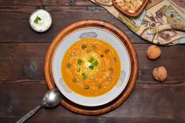 pumpkin soup puree with seeds and cream on a wooden table view from above