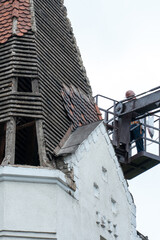 Workers stand on a special platform lifting tower. Repair of the facade of the building at a height, replacement of roof tiles, high-rise work life-threatening. Compliance with safety rules