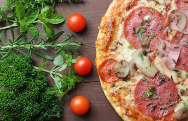 Pizza mit Schinken, Salami und Champignons und Basilikum, Rosmarin, Petersilie, Thymian und Tomaten