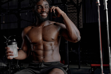 Fototapeta na wymiar Relaxed Afro American Man Talking On Phone, Having Rest Affter Training, Intense Workout At Gym, Sit Smiling, Enjoying Break Time. Healthy Lifestyle, Sport, Leisure, People Concept. Portrait