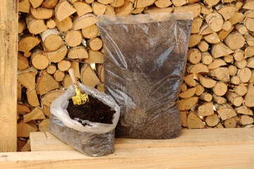 Agrotematics: presentation of packaging with soil, soil, fertilizer against the background of a wall made of birch firewood