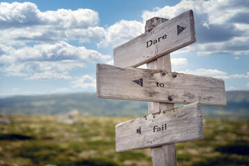 dare to fail text quote on wooden signpost outdoors in nature. Blue sky above.