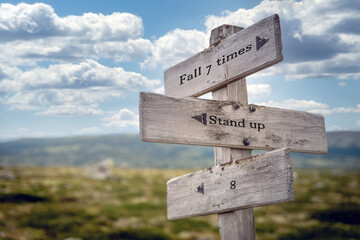 fall 7 times stand up 8 text quote on wooden signpost outdoors in nature. Blue sky above.