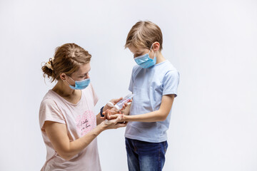 Young woman applying hand-sanitizer anti-bacterial gel on son's hands