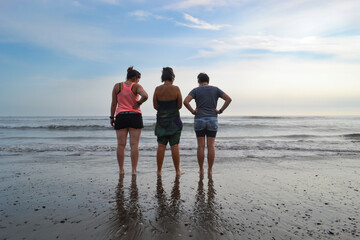 women look for stones, shells, emerita analoga, on the shore of a beach at sunset.