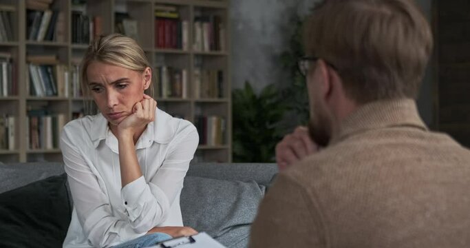 Upset female suffering loneliness after husband separation divorce sharing depression symptoms with psychotherapist at session. Man professional mental doctor taking psychotherapy support and care
