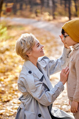 Pretty woman cares of little child boy,son. lovely mother hugging stroking son. caucasian family in caots after walk in forest or park on autumn season. childhood, lifestyle, family concept