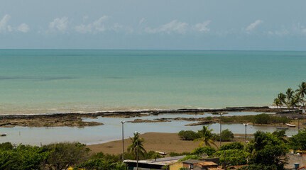 vista de cima de pria com muitas pedras que desaparecem com a maré alta