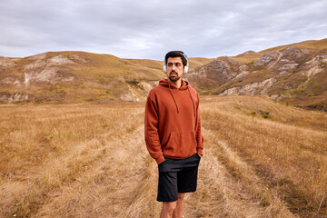 Naklejka premium Thoughtful Calm Man Listen To Music, Walking Alone In Field In countryside at summer or autumn season. fit caucasian male thinking about life, having rest far from civilization, city