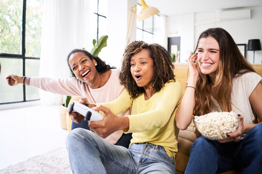 Group Of Young Friends Play Video Games Together At Home. Only Women Gamers Celebrating And Eating Popcorns. 