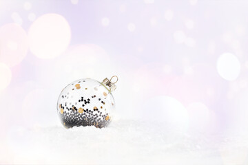 Shiny, silver glass Christmas ball on snow on a light background. Glittering,Shiny...