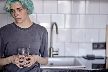 Beautiful caucasian female drinking water in kitchen, alone at home, melancholic mood. attractive...
