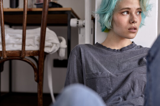 Depressed sad worried young woman in casual wear sit on bedroom floor alone troubled with loneliness, upset about solitude mental problem look at window think of abortion regret bad mistake concept
