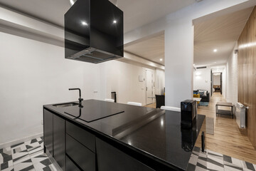 Black marble kitchen island with hob and hood in a vacation rental apartment