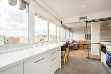 Kitchen with long white worktop and large window overlooking the city in a vacation rental apartment